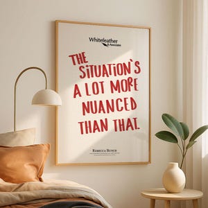 May include: A framed poster with the text "THE SITUATION'S A LOT MORE NUANCED THAN THAT" in red, with the Whitefeather & Associates logo at the top. The poster is in a bedroom setting with a lamp and a side table.