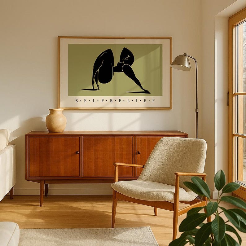 May include: A framed horizontal wall art print featuring a stylized black silhouette of a person in a yoga pose against a muted olive green background, with the text S E L F B E L I E F printed in black capital letters centered below the figure.