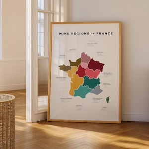 Puede incluir: Un póster enmarcado titulado "Wine Regions of France" presenta un mapa colorido de Francia, destacando varias áreas productoras de vino. El mapa está en tonos de marrón, rojo, rosa, verde y amarillo, con cada región etiquetada.