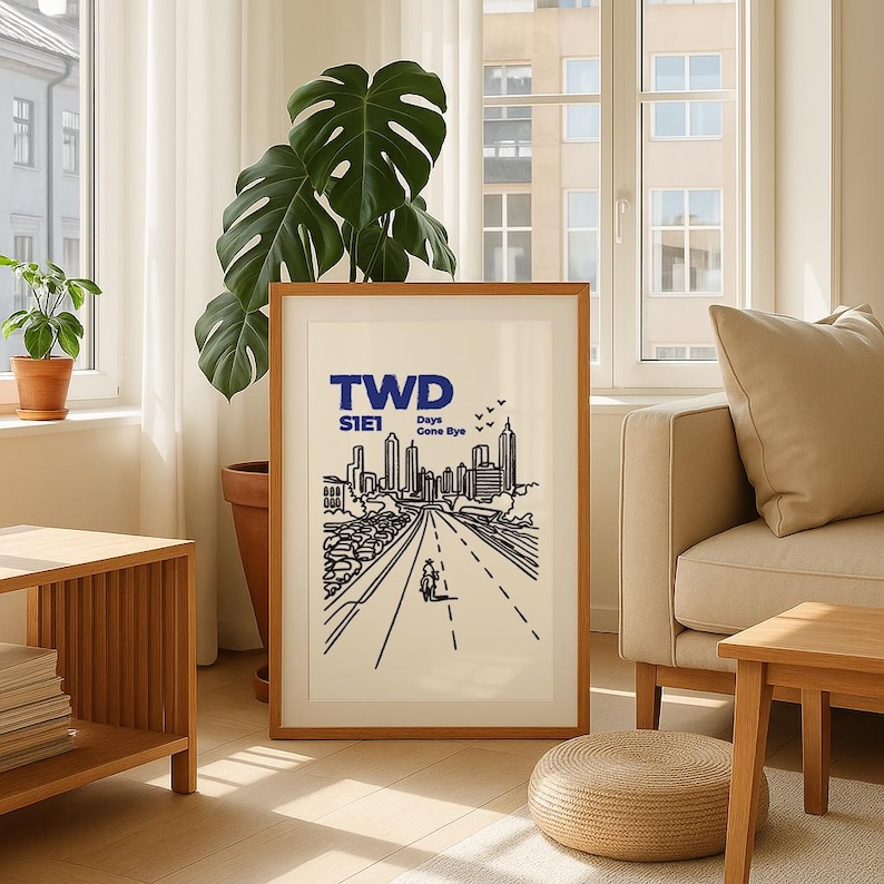 May include: A framed art print featuring a black and white illustration of a city skyline with a road in the foreground. The text "TWD S1E1 Days Gone Bye" is printed in blue at the top. The print is displayed in a living room setting.