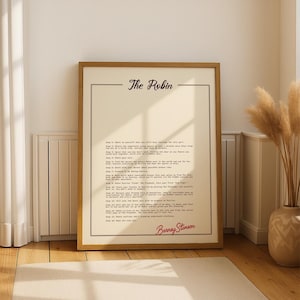 Op de afbeelding: Een ingelijste print met de titel "The Robin" in een schreeflettertype. De print bevat een lijst met stappen in zwarte letters, met de handtekening "Barney Stinson" in rood script onderaan. De lijst is lichtbruin.