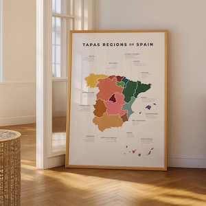 Puede incluir: Un mapa enmarcado titulado "TAPAS REGIONS OF SPAIN" con un marco de madera. El mapa muestra las regiones de España en varios colores. El mapa está apoyado contra una pared en una habitación con suelo de madera.