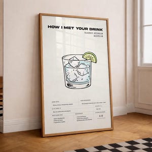 May include: A framed print with the text "HOW I MET YOUR DRINK" and "BARNEY STINSON EDITION." The print features a cocktail illustration with ice cubes and a lime wedge. The print is in a wooden frame.