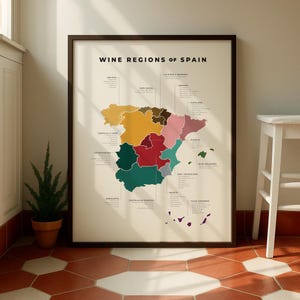 Puede incluir: Un mapa enmarcado titulado "Regiones vinícolas de España" con una colorida ilustración de las regiones del país. El mapa está en un marco marrón oscuro, y las regiones se distinguen por diferentes colores.