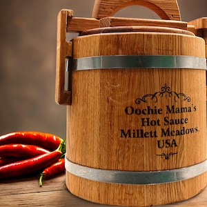 May include: A wooden barrel with a metal band and a handle. The barrel is labelled "Oochie Mama's Hot Sauce Millett Meadows, USA".