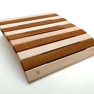 Può includere: Un cuscino per sedile in legno curvo con doghe di legno chiaro e scuro alternate. Il cuscino è realizzato in legno naturale e ha una finitura liscia e lucida.