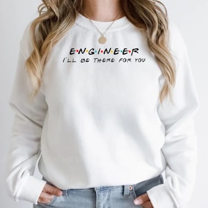 May include: White sweatshirt with the word "ENGINEER" in black, with the letters in the style of the TV show "Friends". Below the word "ENGINEER" is the phrase "I'LL BE THERE FOR YOU" in black. The sweatshirt is a crew neck.