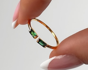 May include: A gold ring with two green rectangular gemstones.