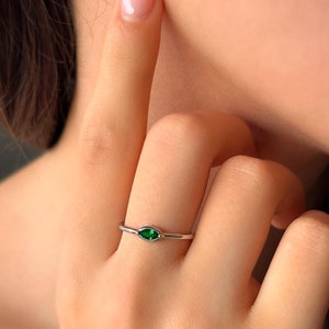 Könnte beinhalten: Ein silberner Ring mit einem kleinen, markisenförmigen grünen Edelstein.