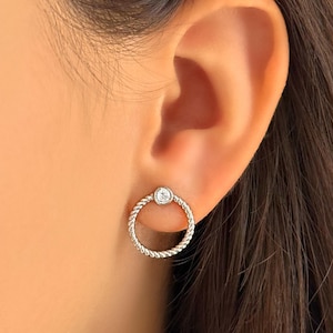 May include: Silver hoop earrings with a small clear stone set in the center of the hoop.