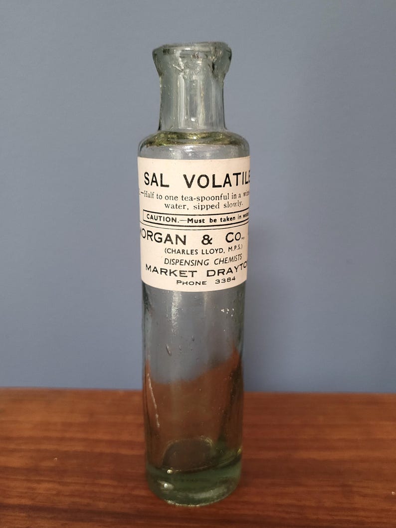 Peut inclure: Une bouteille d'apothicaire en verre transparent avec un corps cylindrique et un goulot &eacute;troit. Une &eacute;tiquette en papier blanc est enroul&eacute;e autour du centre, imprim&eacute;e avec du texte noir indiquant SAL VOLATILE, des instructions et Morgan & Co.