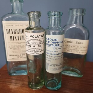 Peut inclure: Quatre flacons d'apothicaire vintage en verre transparent avec &eacute;tiquettes. Les &eacute;tiquettes portent des inscriptions telles que Diarrhoea Mixture, Sal Volatile, Kaolin & Morphine Mixture et Cattle Salts. Les flacons ont des formes vari&eacute;es, dont un de 200 ml.