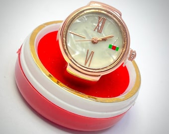 Presenta un acabado metálico en tono oro rosa con una esfera de reloj con anillo blanco.