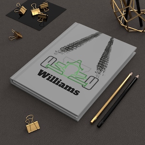 Peut inclure: Un journal gris avec le mot "Williams" et un dessin de voiture de course vert et noir. Des traces de pneus noires sont imprimées au-dessus de la voiture. Des crayons dorés et noirs et des trombones dorés sont sur la surface gris foncé.
