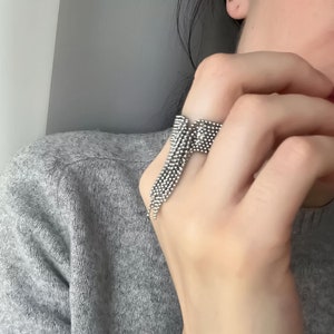 May include: A silver ring with a fringe design. The ring is made of small, round beads that are connected together to form a cascading fringe.