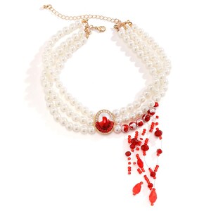 May include: A white pearl necklace with a red and white jeweled pendant and a red beaded fringe.