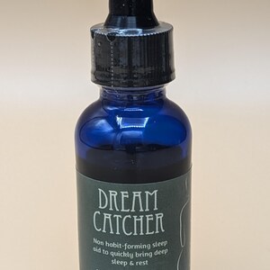 May include: A blue glass bottle with a black dropper top and a green label that reads "DREAM CATCHER" and "Non habit-forming sleep aid to quickly bring deep sleep & rest" and "Net Wt 1 oz. (22.679 g)".
