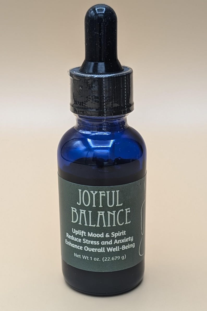 May include: A blue glass bottle with a black dropper top. The bottle has a green label that reads "JOYFUL BALANCE", "Uplift Mood & Spirit", "Reduce Stress and Anxiety", "Enhance Overall Well-Being", and "Net Wt 1 oz. (22.679 g)".