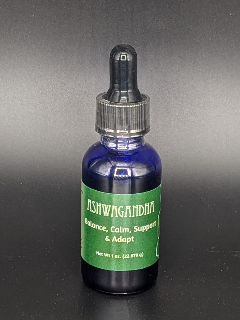 May include: A blue glass bottle with a black dropper top. The bottle is labeled "Ashwagandha" and contains a liquid. The label also says "Balance, Calm, Support & Adapt" and "Net Wt 1 oz. (22.679 g)".