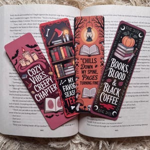 May include: Four decorative bookmarks with spooky themes are displayed open on a book. The bookmarks feature text and illustrations of candles, books, axes, and pumpkins. The color palette includes red, orange, and black.