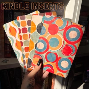 May include: A collection of colorful Kindle inserts with retro geometric patterns. The inserts feature designs with orange, red, blue, and yellow circles, squares, and wavy lines. The text "KINDLE INSERTS" is displayed at the top.