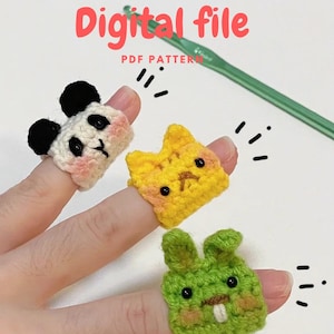 Op de afbeelding: Drie handgemaakte haakringen in de vorm van dieren: een panda, een kat en een konijn. De pandaring is zwart en wit, de kat is geel en het konijn is groen. De ringen zitten aan de vingers van een persoon. De tekst in de afbeelding luidt "Digital file PDF pattern."