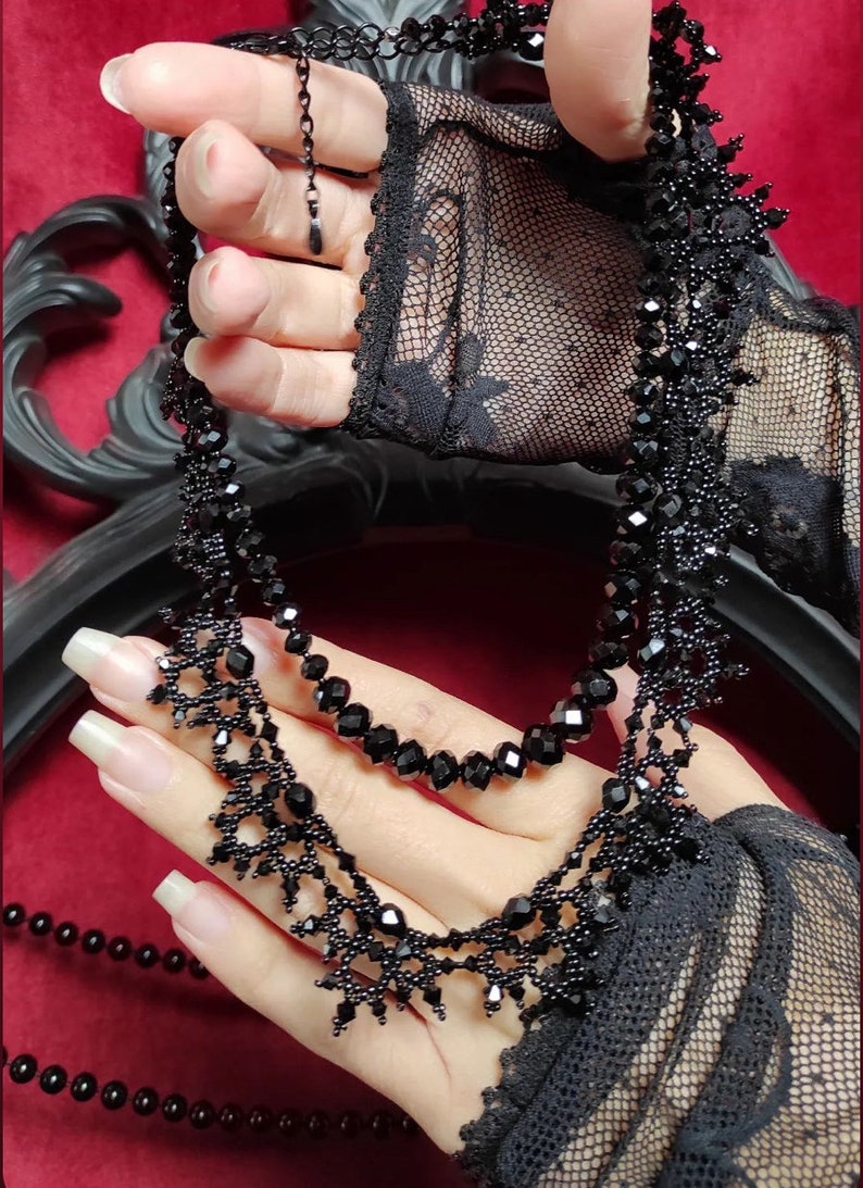 A woman's hands holding up the Victorian necklace in Jet Black, as well as the Nocturne necklace in Jet Black (sold seperately) - both by handmade by Isabel Design Studio.