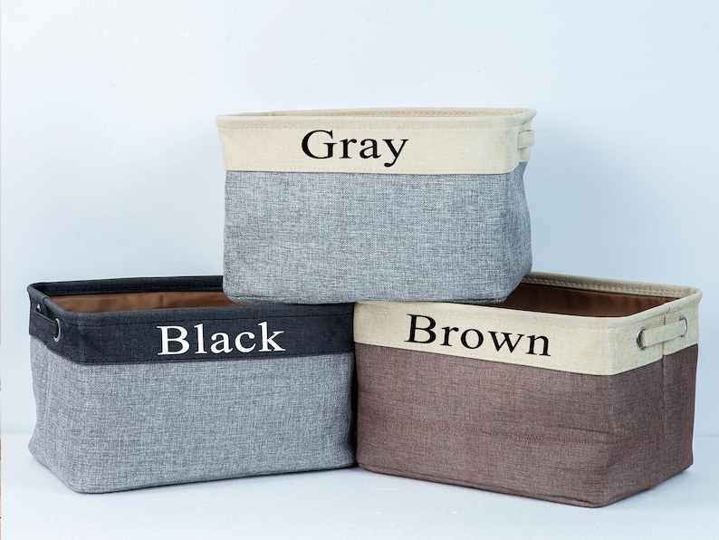 May include: Three fabric storage bins with black labels. The bins are gray, black, and brown. The labels read "Gray", "Black", and "Brown".