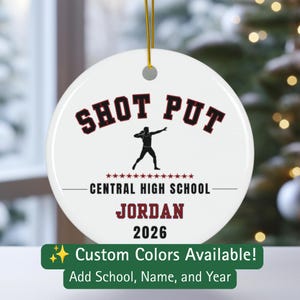 May include: A white circular ceramic ornament featuring a black silhouette of a shot put athlete. The text reads SHOT PUT in black, CENTRAL HIGH SCHOOL in black, JORDAN in maroon, and 2026 in black. A gold string is attached to the top hole.