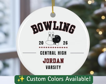 May include: A round white ceramic ornament with a gold string, featuring the text BOWLING, 20 26, CENTRAL HIGH, JORDAN, and VARSITY in black and maroon, along with a graphic of a bowling ball and pins and a row of small maroon stars.