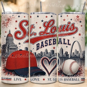 May include: A cylindrical tumbler with a straw featuring a St. Louis baseball theme. The design includes a red and blue baseball cap, a white baseball, the St. Louis skyline with the Gateway Arch, a heart outline, and text reading St. Louis Baseball.