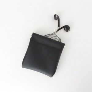 May include: A black leather pouch with a drawstring closure, containing a pair of black and gold wired earbuds.