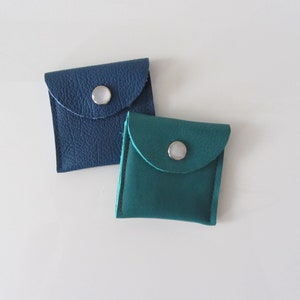 Puede incluir: Dos peque&ntilde;as bolsas de cuero con cierre de presi&oacute;n. Una bolsa es azul y la otra es turquesa.