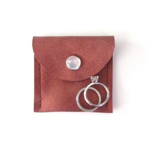 May include: A small brown leather pouch with a snap closure, containing two silver rings. One ring has a small diamond.