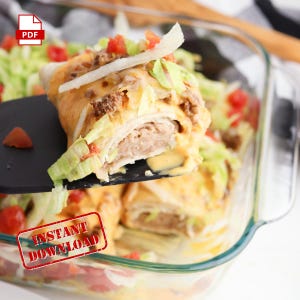 Peut inclure: Gros plan sur un plat à gratin rempli d'un gratin de style taco en couches et au fromage. Une spatule soulève une portion du gratin, révélant les couches de bœuf haché, de fromage et de laitue. Le gratin est garni de laitue hachée, de tomates en dés et de fromage râpé. Le texte "INSTANT DOWNLOAD" est estampillé en rouge sur l'image.