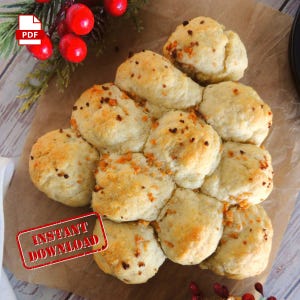 Könnte beinhalten: Eine weihnachtliche Anordnung von goldbraunen Brötchen in Form eines Weihnachtsbaums, bestreut mit Kräutern und Gewürzen. Die Brötchen sind auf einer braunen, mit Papier ausgelegten Oberfläche angeordnet.