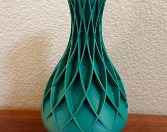 May include: A teal green ceramic vase with a geometric, lattice-like design. The vase has a round base and a narrow neck.