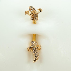 May include: Gold body jewelry with a jeweled lizard design on each end.