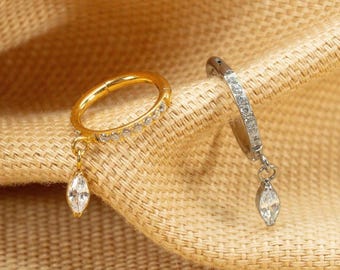 May include: Two gold and silver hoop earrings with dangling marquise-shaped crystal accents.