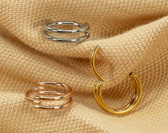 May include: Three hoop earrings in different colors: silver, gold, and rose gold. The earrings are all made of metal and have a simple, elegant design.