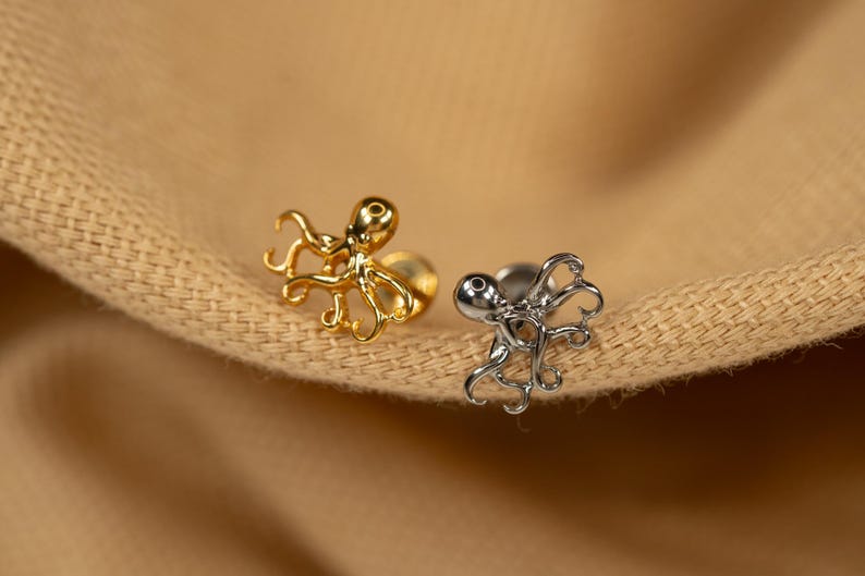 May include: Two octopus shaped body jewelry pieces. One is gold and the other is silver.