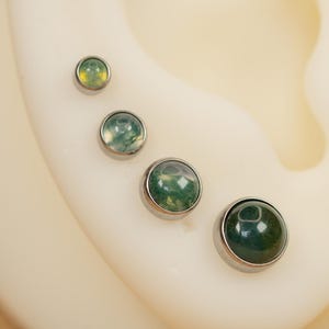 Puede incluir: Cuatro pendientes de &aacute;gata verde y blanca de diferentes tama&ntilde;os con engastes plateados.