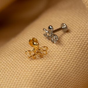 May include: Two octopus shaped body jewelry pieces. One is gold and the other is silver.
