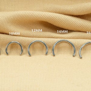May include: A set of six silver hoop earrings in different sizes, ranging from 8mm to 16mm. The earrings are displayed on a beige fabric background.