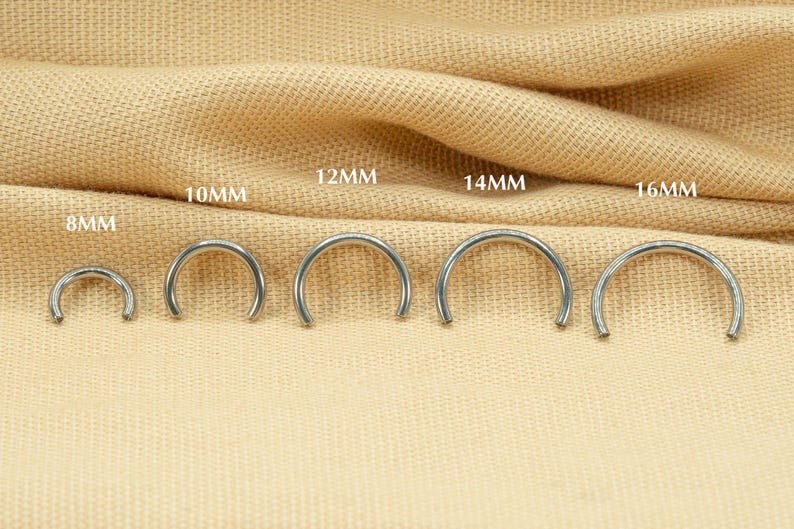 May include: A set of six silver hoop earrings in different sizes, ranging from 8mm to 16mm. The earrings are displayed on a beige fabric background.