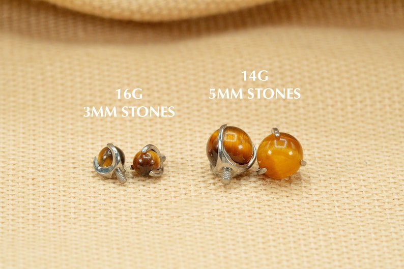 May include: Two pairs of tiger's eye gemstone earrings. The smaller pair is 16 gauge with 3mm stones. The larger pair is 14 gauge with 5mm stones.