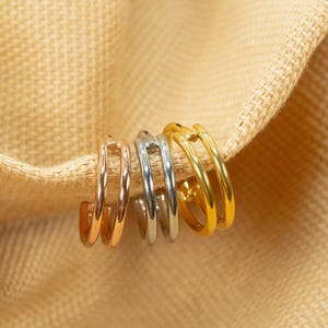 以下が含まれることがあります： ゴールド、シルバー、ローズゴールドの異なる金属仕上げのフープイヤリング4つ。イヤリングは互いに重ねられています。