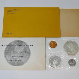May include: A 1968 Republic of Panama Proof Set, including various coins in a clear plastic sleeve. The set is accompanied by a yellow envelope and a white card with text about the set's mintage and buyers.