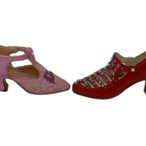 Pode incluir: Um par de sapatos de estilo vintage. Um é rosa com tira em T e bordado floral. O outro é vermelho com um design recortado e salto pequeno. Ambos os sapatos têm um salto pequeno.