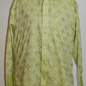 May include: A light green button-down shirt with a floral pattern. The long-sleeved shirt has a classic collar and buttoned cuffs. The fabric has a subtle texture, and the shirt is displayed on a mannequin.